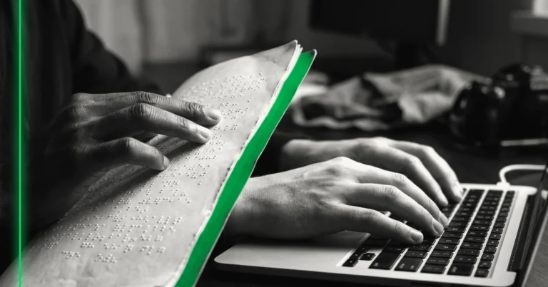 Une main lit une page en braille pendant que l'autre repose sur le clavier d'un ordinateur portable.