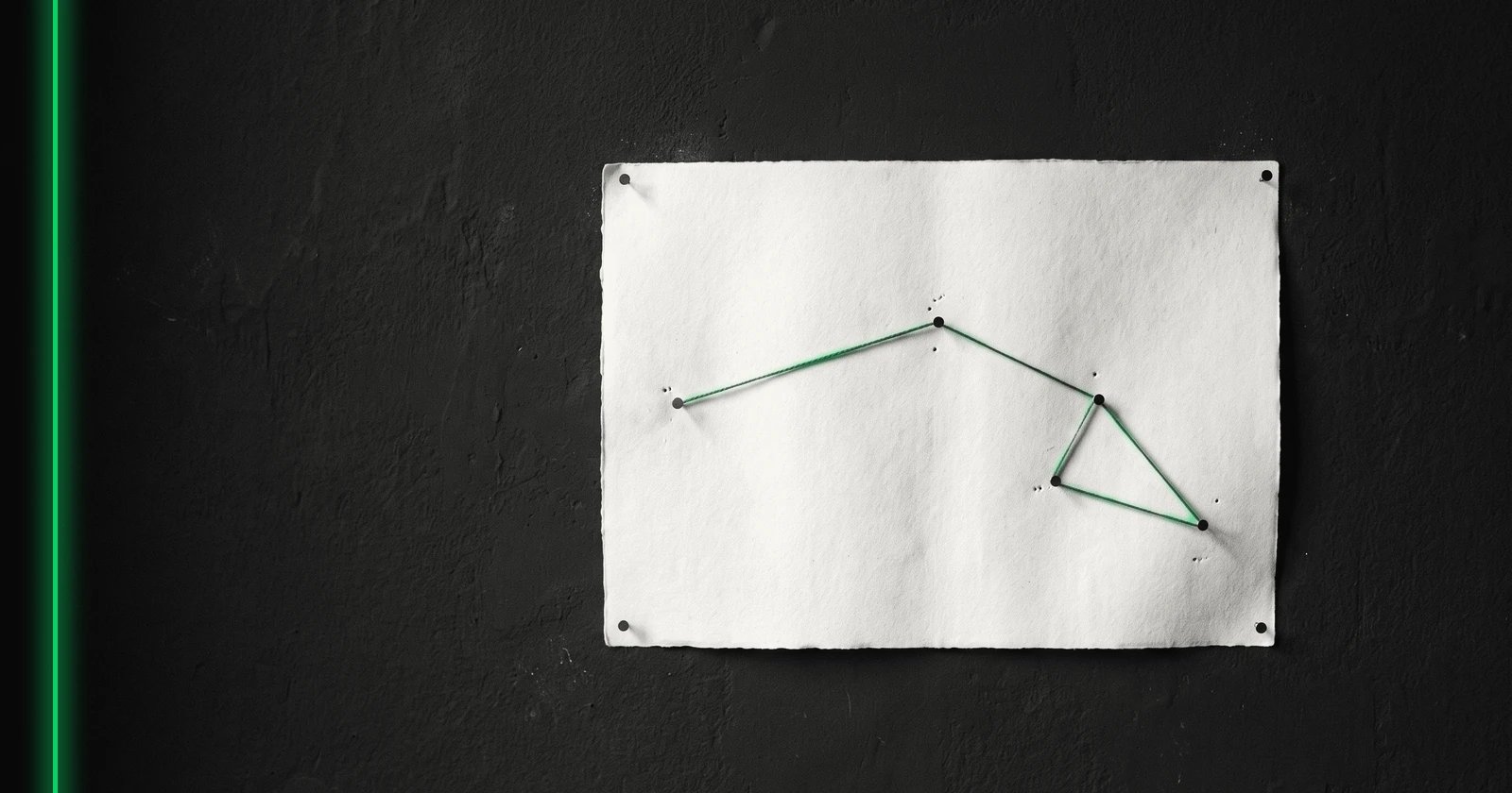 Une carte vierge épinglée au mur, un fil tendu relie les épingles et trace un itinéraire.